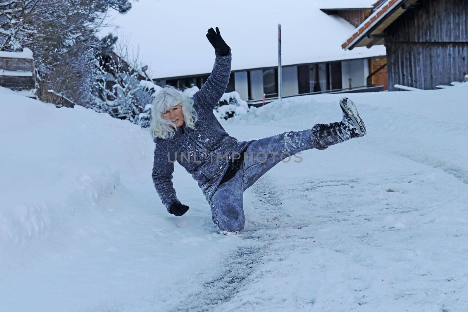 Rutschgefahr auf einer glatten Straße im Winter. Eine Frau ist auf dem Schnee ausgerutscht und hingefallen