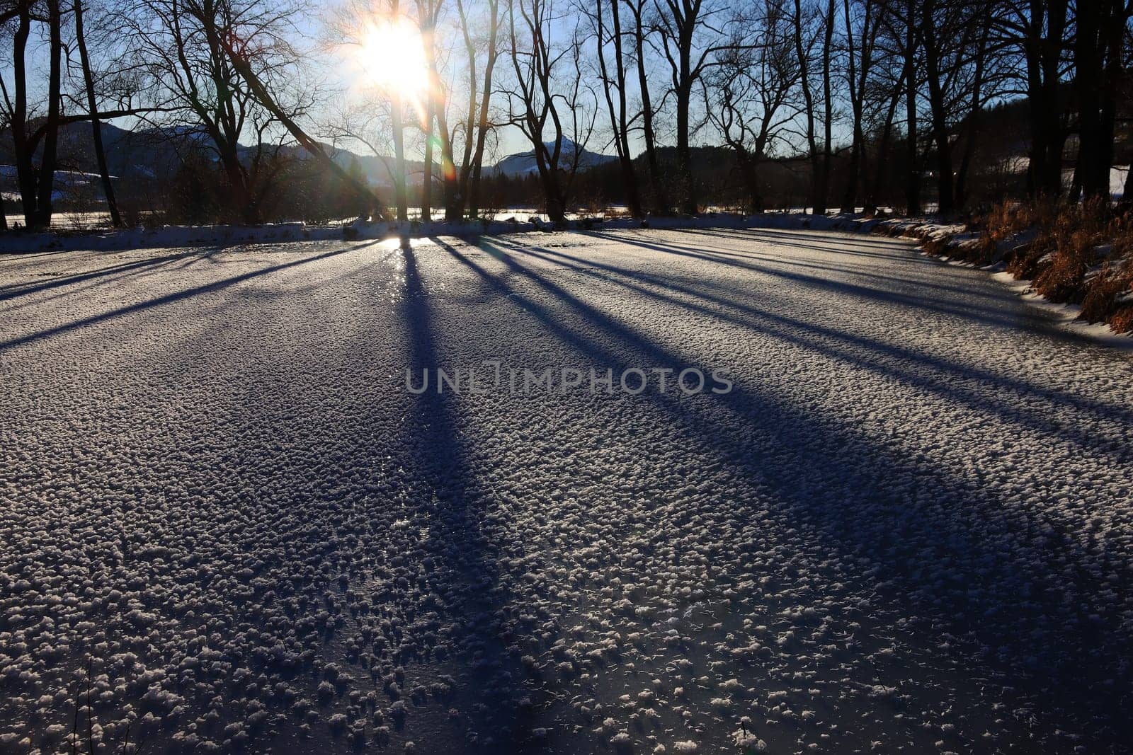 Ein gefrorener See mit Licht und Schatten im Gegenlicht der Sonne im Winter
