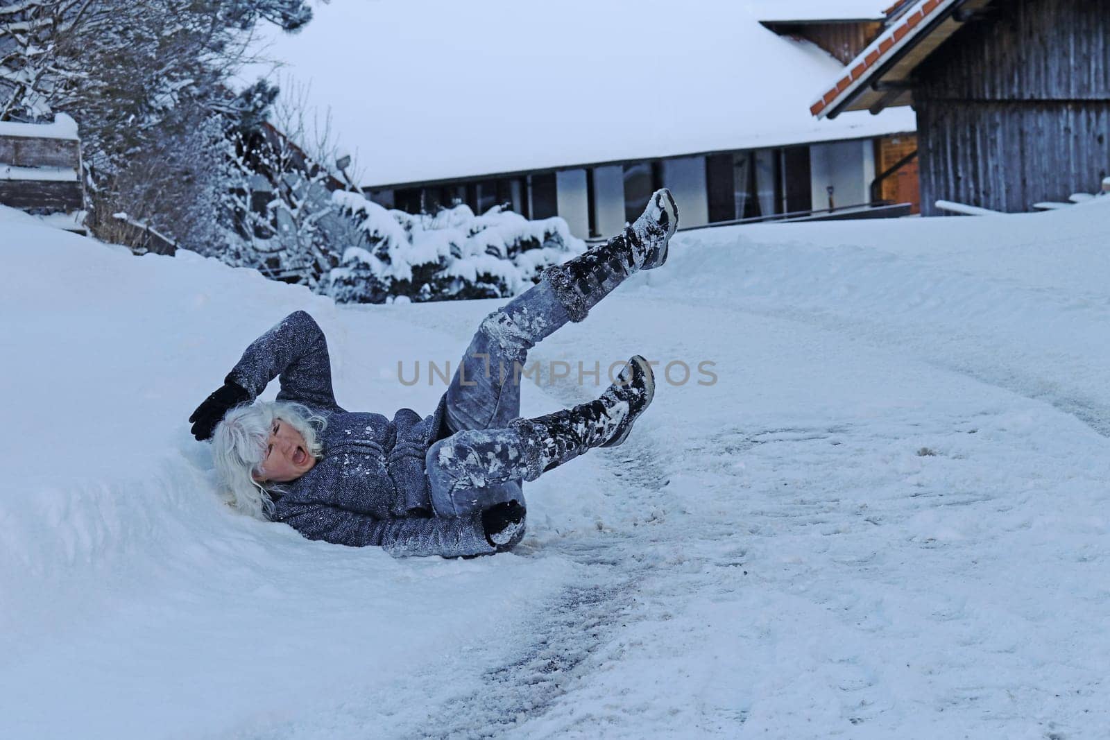 Rutschgefahr auf einer glatten Straße im Winter. Eine Frau ist auf dem Schnee ausgerutscht und hingefallen