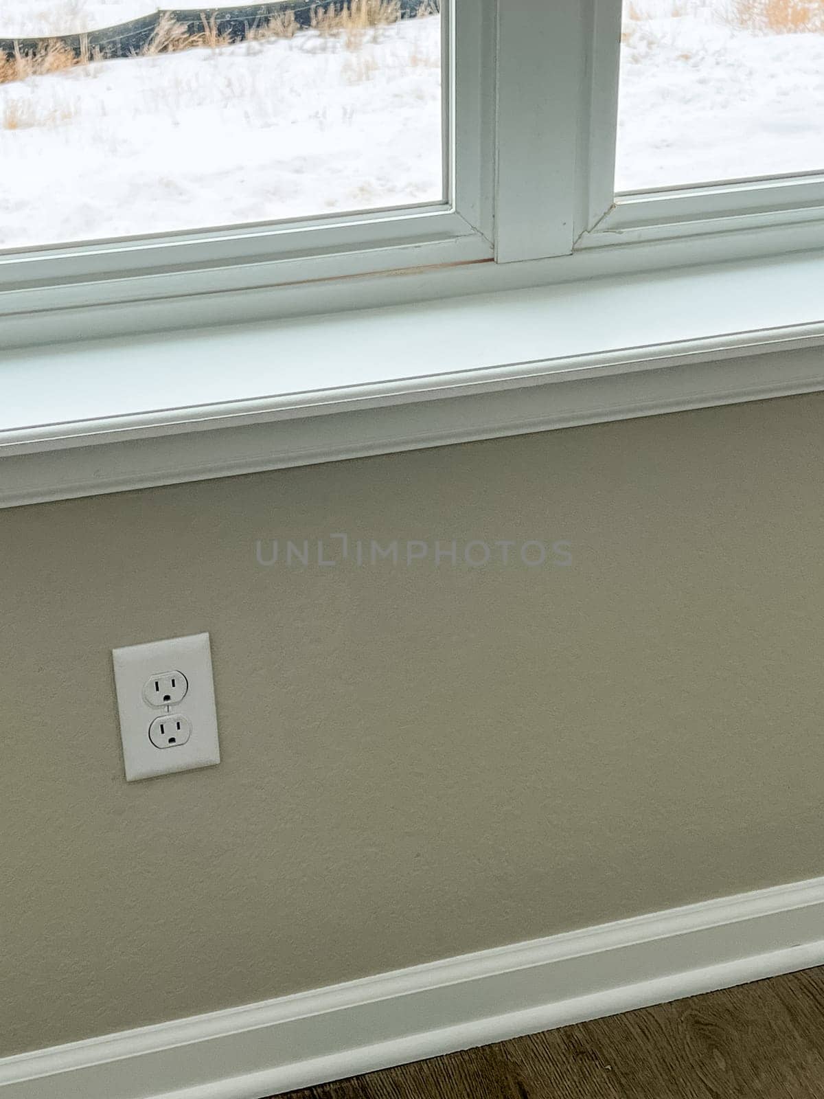 Castle Pines, Colorado USA - January 18, 2023-Close-up of a clean wall outlet beneath a large window with a white window ledge in a newly constructed single-family home. The neutral-colored walls and baseboard highlight the modern design and attention to detail in the home.