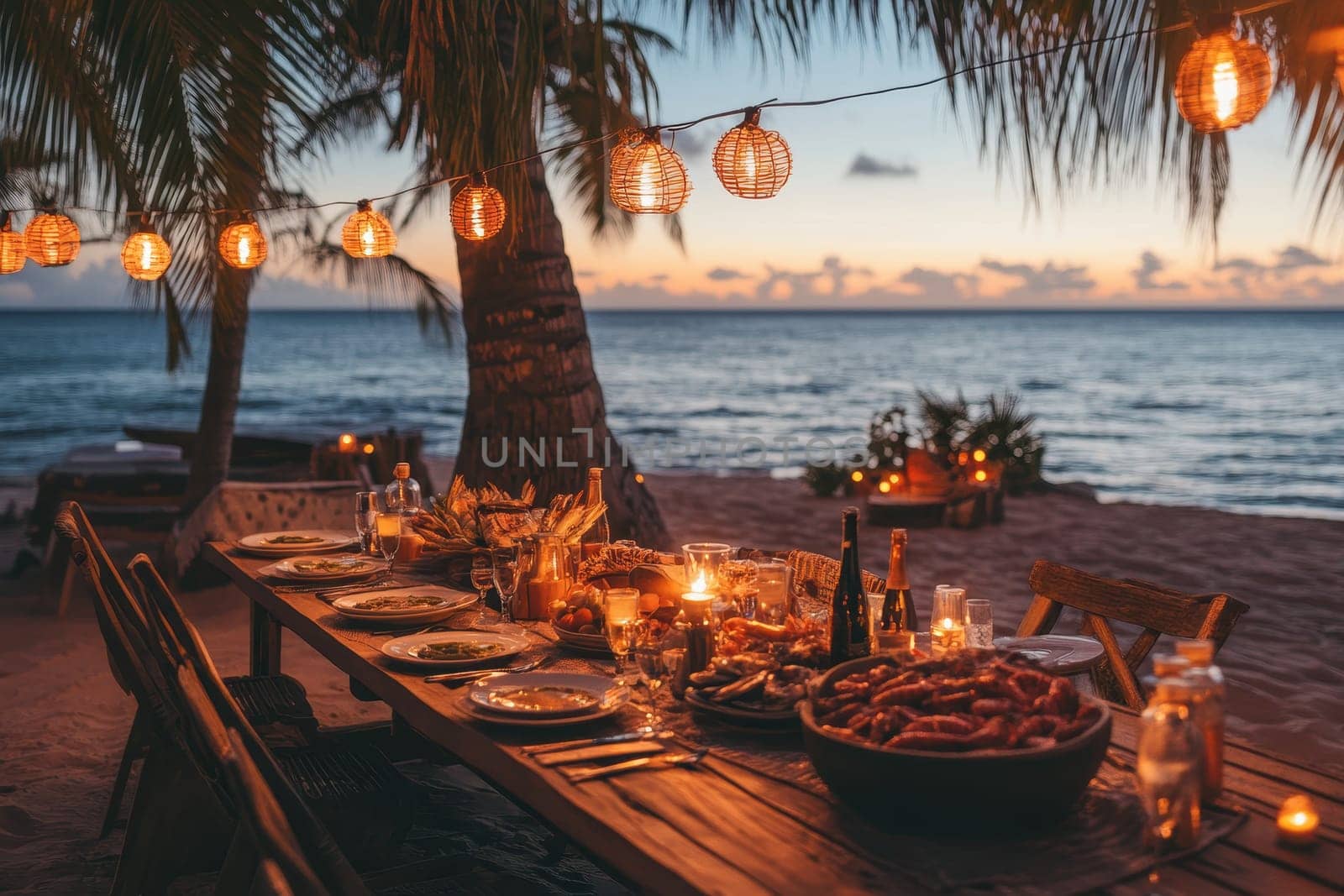 Experience a tranquil beach dinner at sunset featuring a beautifully set table adorned with hanging lanterns, offering a cozy atmosphere for a delicious meal by the ocean.