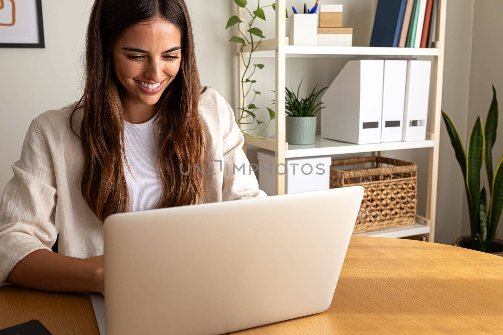 Happy young woman working at home office. Smiling female entrepreneur using laptop. Copy space. by Hoverstock
