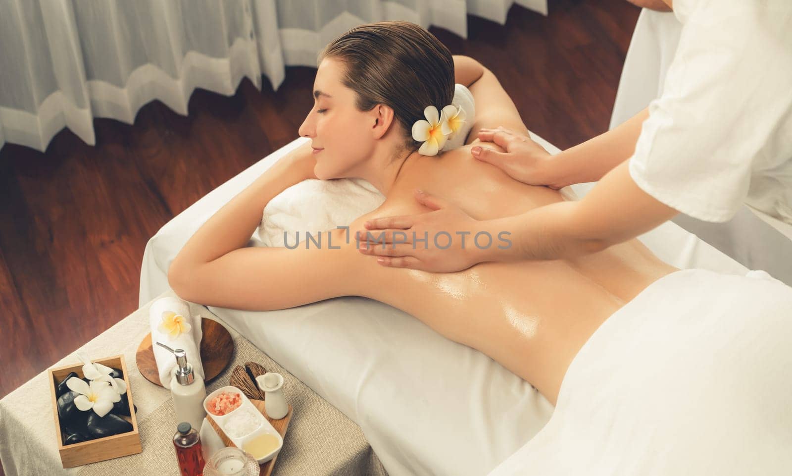 Caucasian woman customer enjoying relaxing anti-stress spa massage and pampering with beauty skin recreation leisure in day light ambient salon spa at luxury resort or hotel. Quiescent