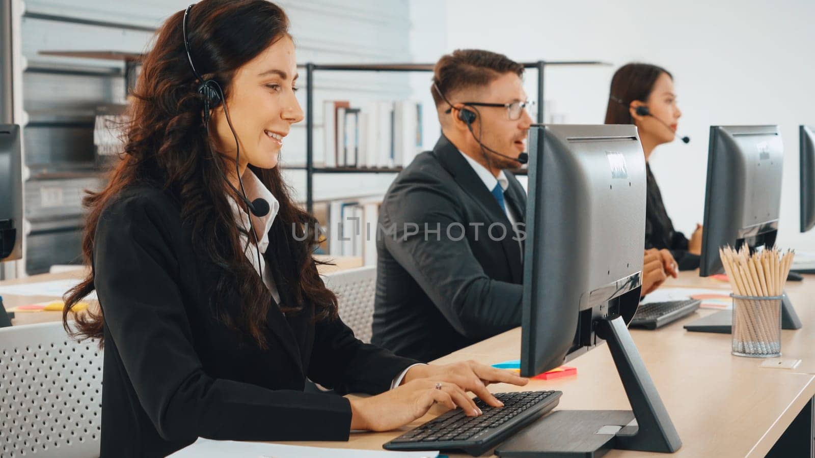 Business people wearing headset working in office to support remote customer or colleague. Call center, telemarketing, customer support agent provide service on telephone video conference call. Jivy