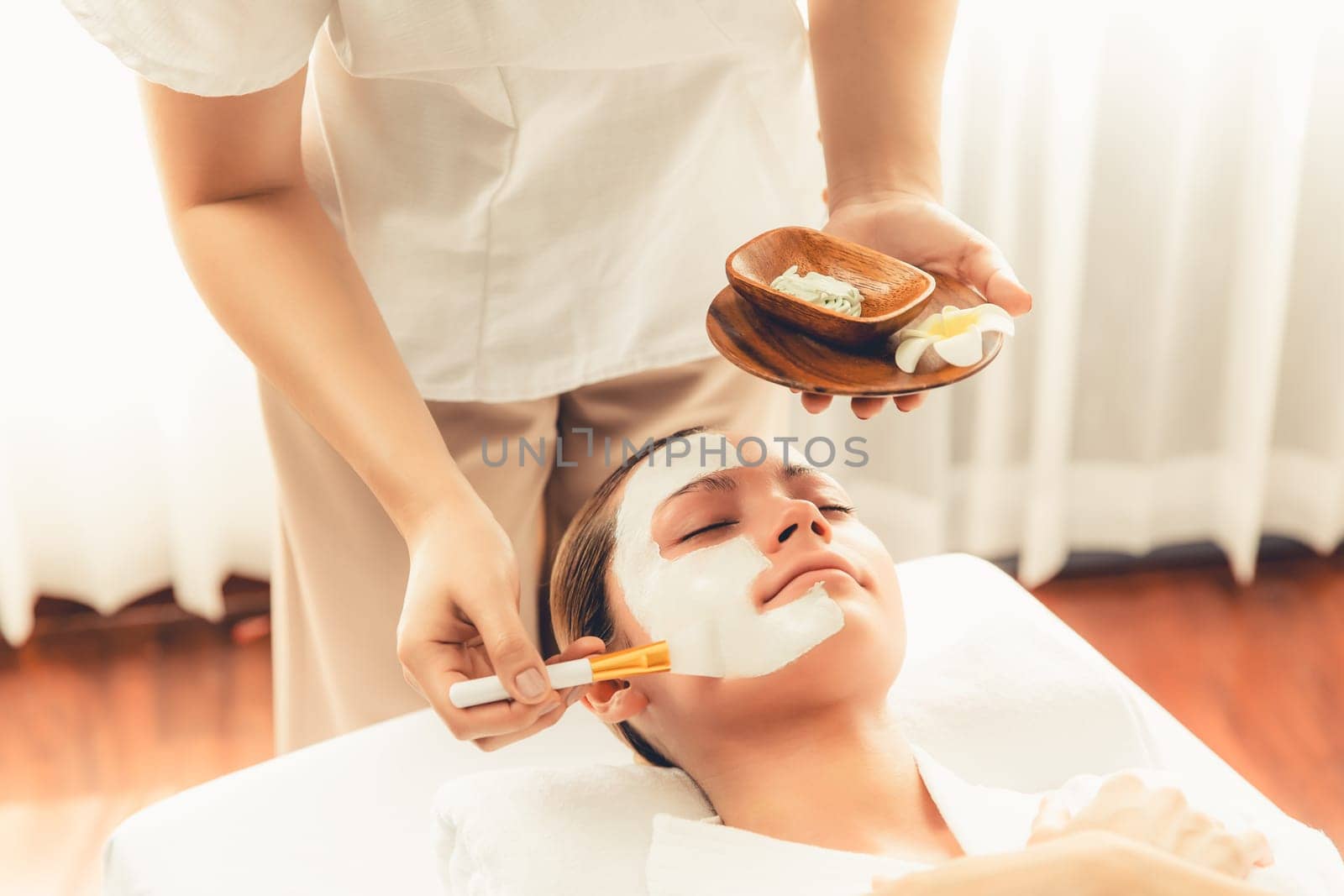 Serene ambiance of spa salon, woman customer indulges in rejuvenating with luxurious face cream massage with modern daylight. Facial skin treatment and beauty care concept. Quiescent