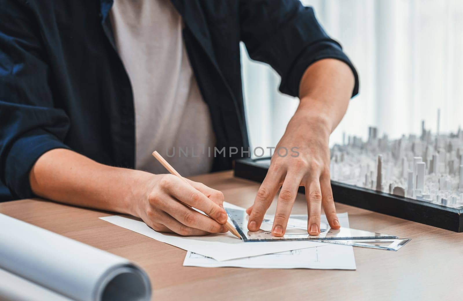 Architect or city planner draws city plan on blueprint, architecture designer plans with miniature cityscape replica on table to visualize the urban planning. Iteration