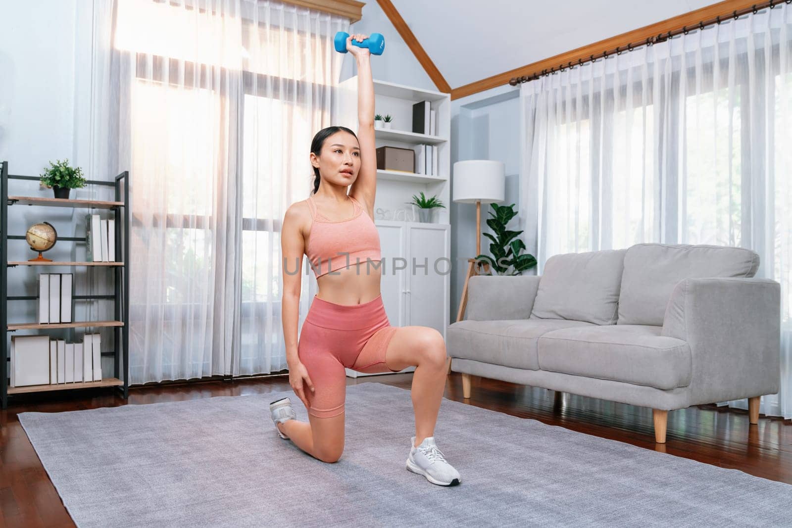 Vigorous energetic woman doing yoga with dumbbell weight exercise at home. by biancoblue