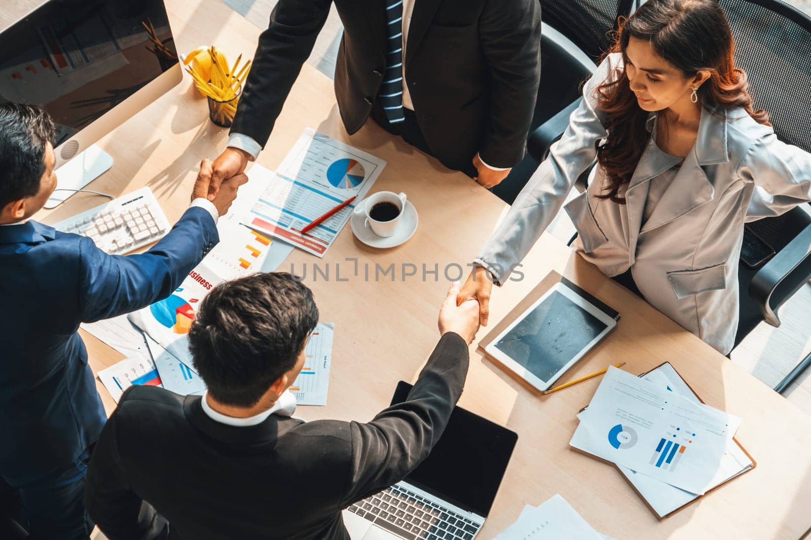 Group business people handshake at meeting table in office together with confident shot from top view . Young businessman and businesswoman workers express agreement of investment deal. Jivy