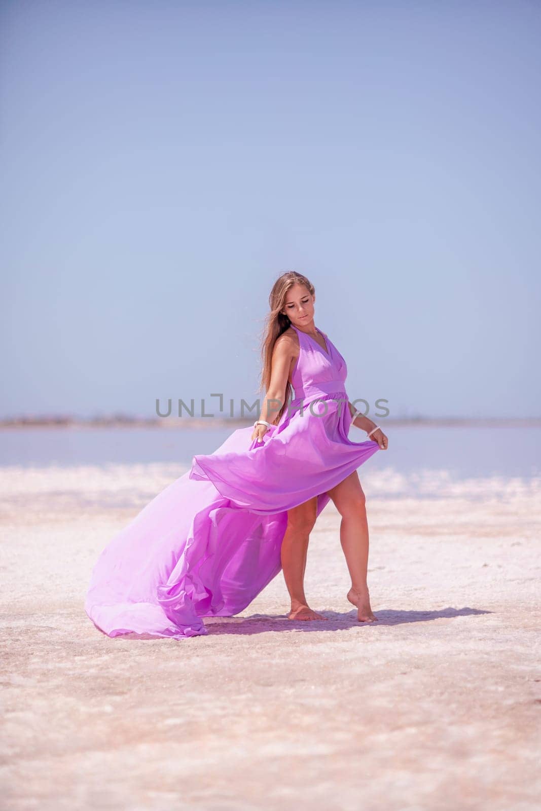 Woman pink salt lake. Against the backdrop of a pink salt lake, a woman in a long pink dress takes a leisurely stroll along the white, salty shore, capturing a wanderlust moment. by Matiunina