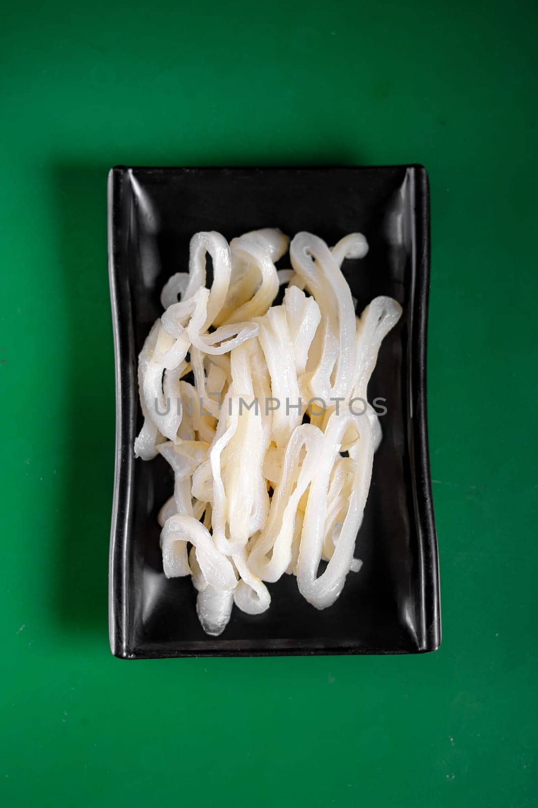 raw white squid on a black plate. View from above. Chinese cuisine, ingredient for hotpot by tewolf