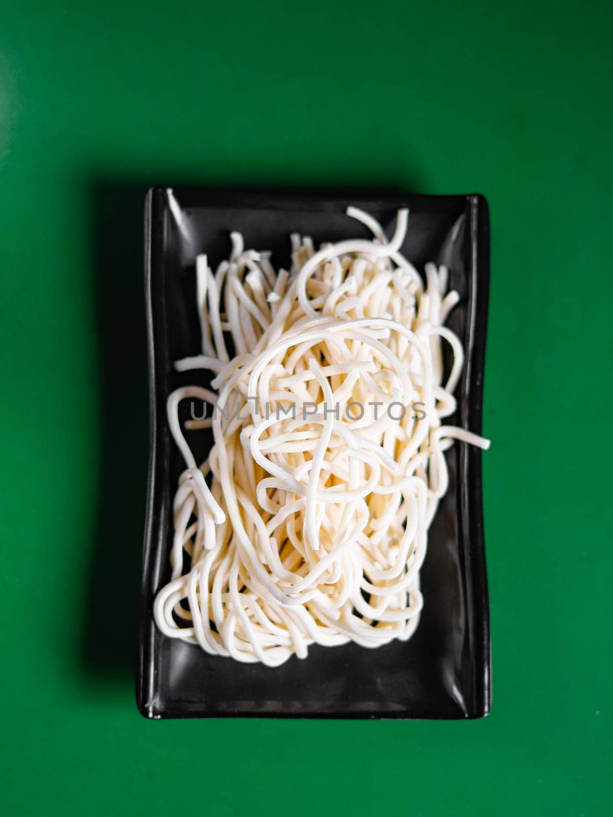 dry and raw flour noodles on a black plate. View from above. Chinese cuisine