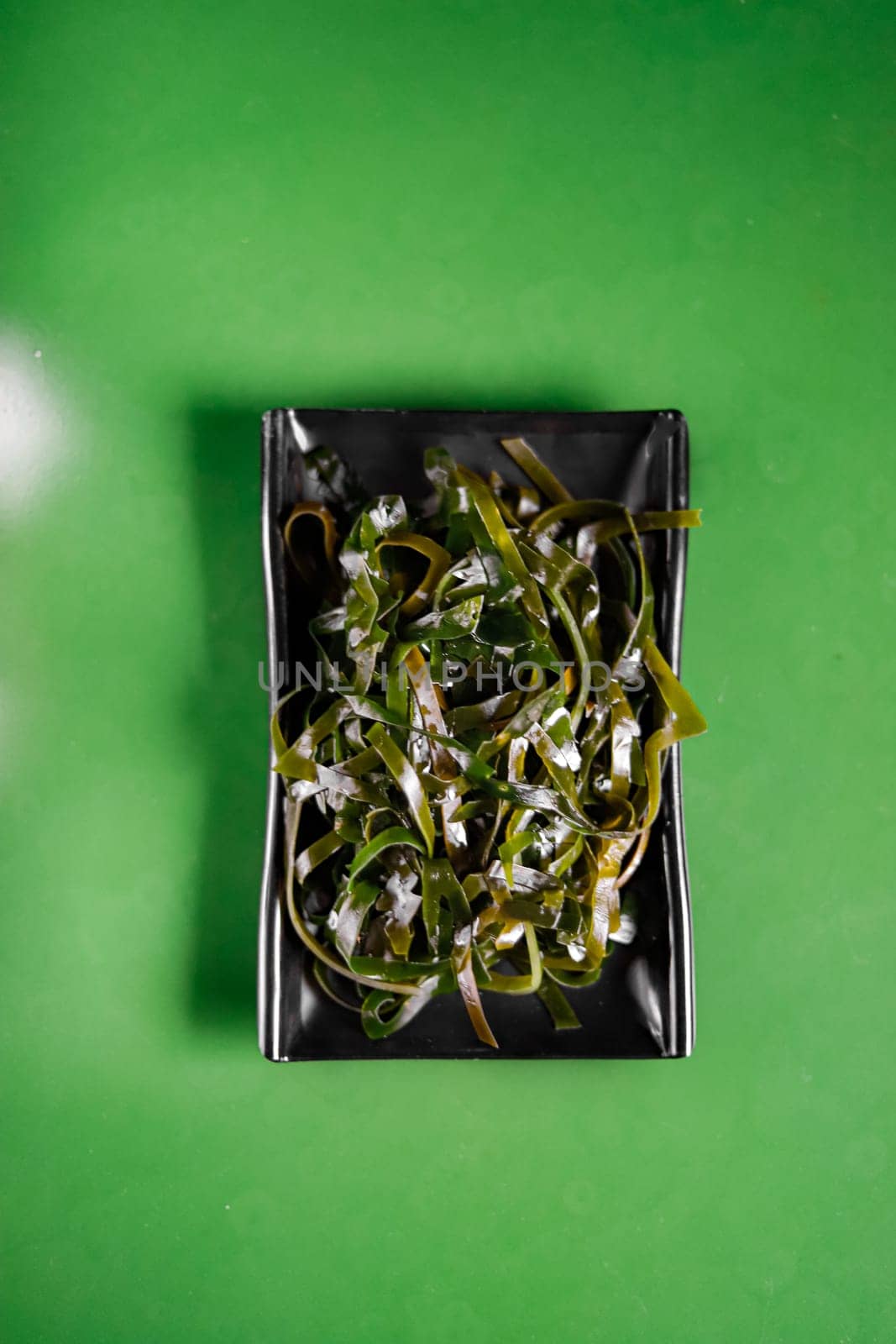 delicious seaweed on a black plate and green background. Garnish. View from above. Chinese cuisine, hotpot ingredient by tewolf