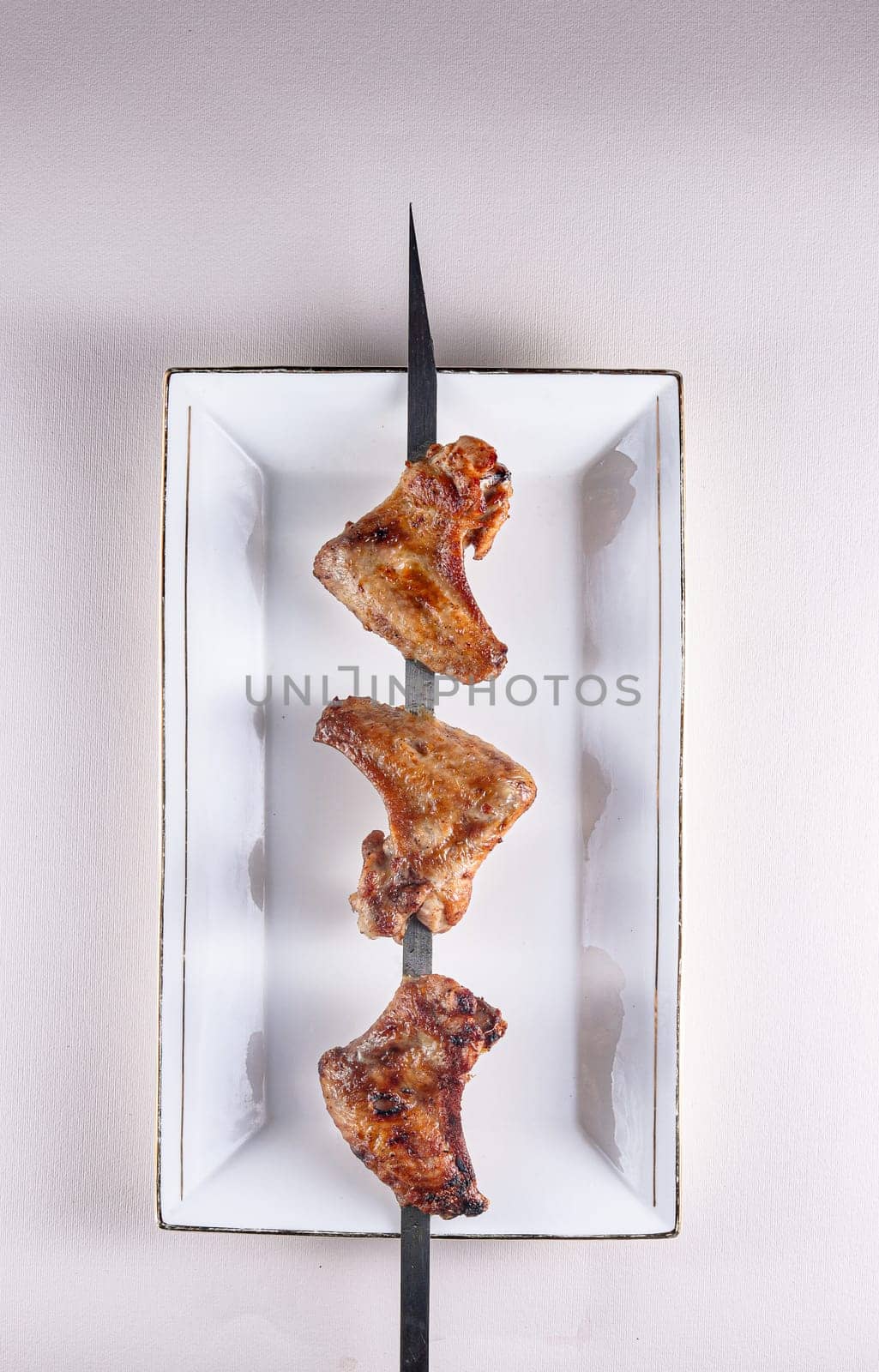 fried chicken wings on a skewer and a white plate. BBQ Chinese cuisine by tewolf