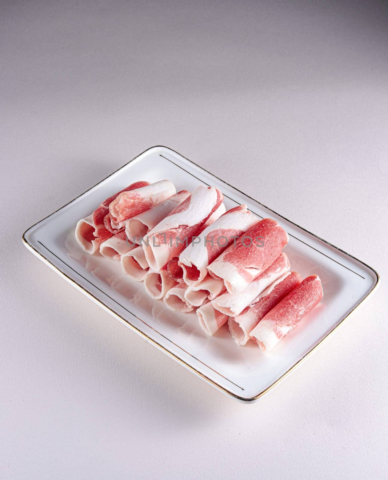 fresh and aesthethic bacon rolls on a white plate. View from above. Chinese cuisine, ingredient for hotpot by tewolf