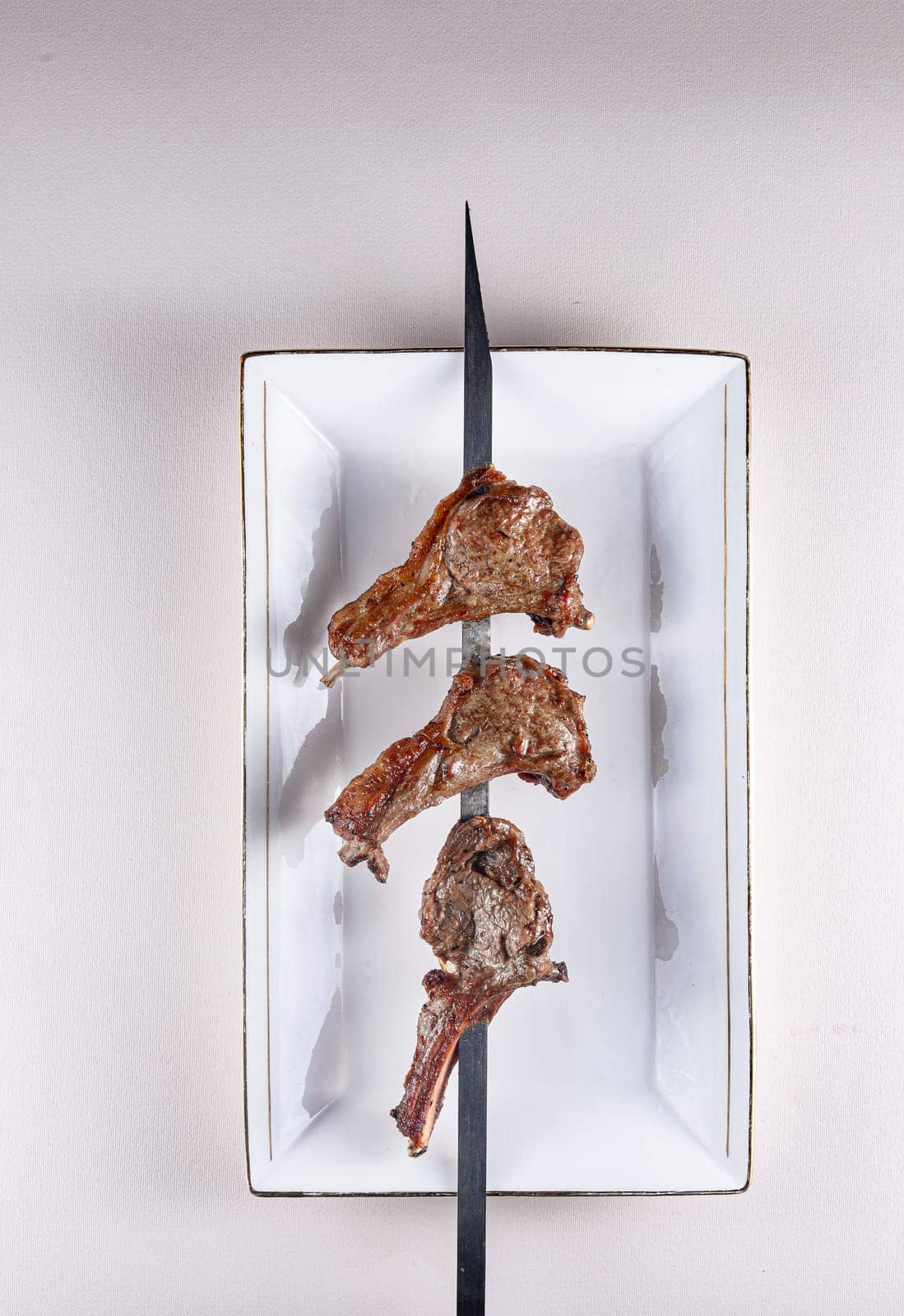 amazing lamb ribs on a skewer on a white plate. . View from above. Chinese cuisine by tewolf