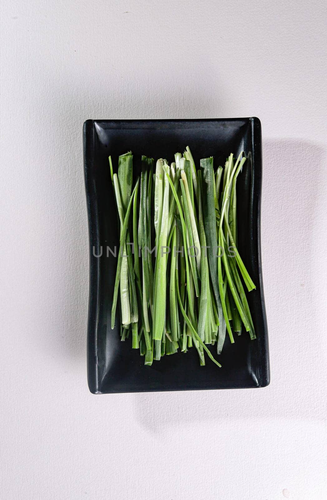 full green onion on a black plate. View from above. Chinese cuisine, ingredient for hotpot by tewolf