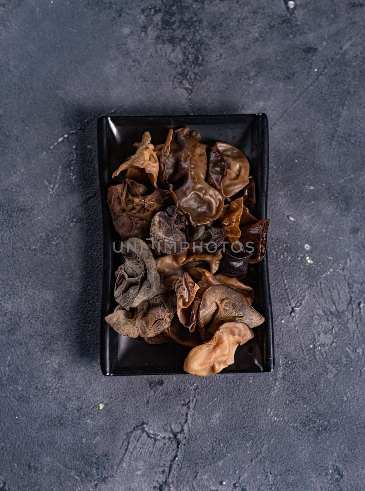 fresh and delicious tree mushrooms on a black plate. View from above. Chinese cuisine, ingredient for hotpot by tewolf