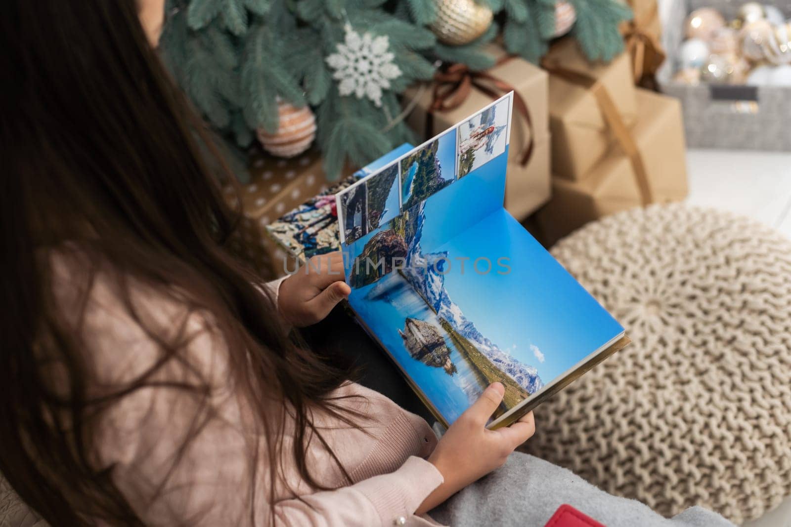 girl teenager photo album and the Christmas tree. Christmas, New Year, memories, family evening.