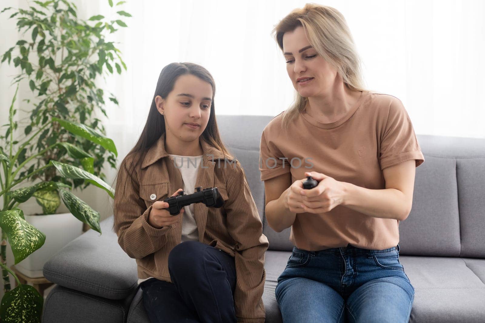 Happy family together. Mother and her child girl playing video games. People having fun at home.