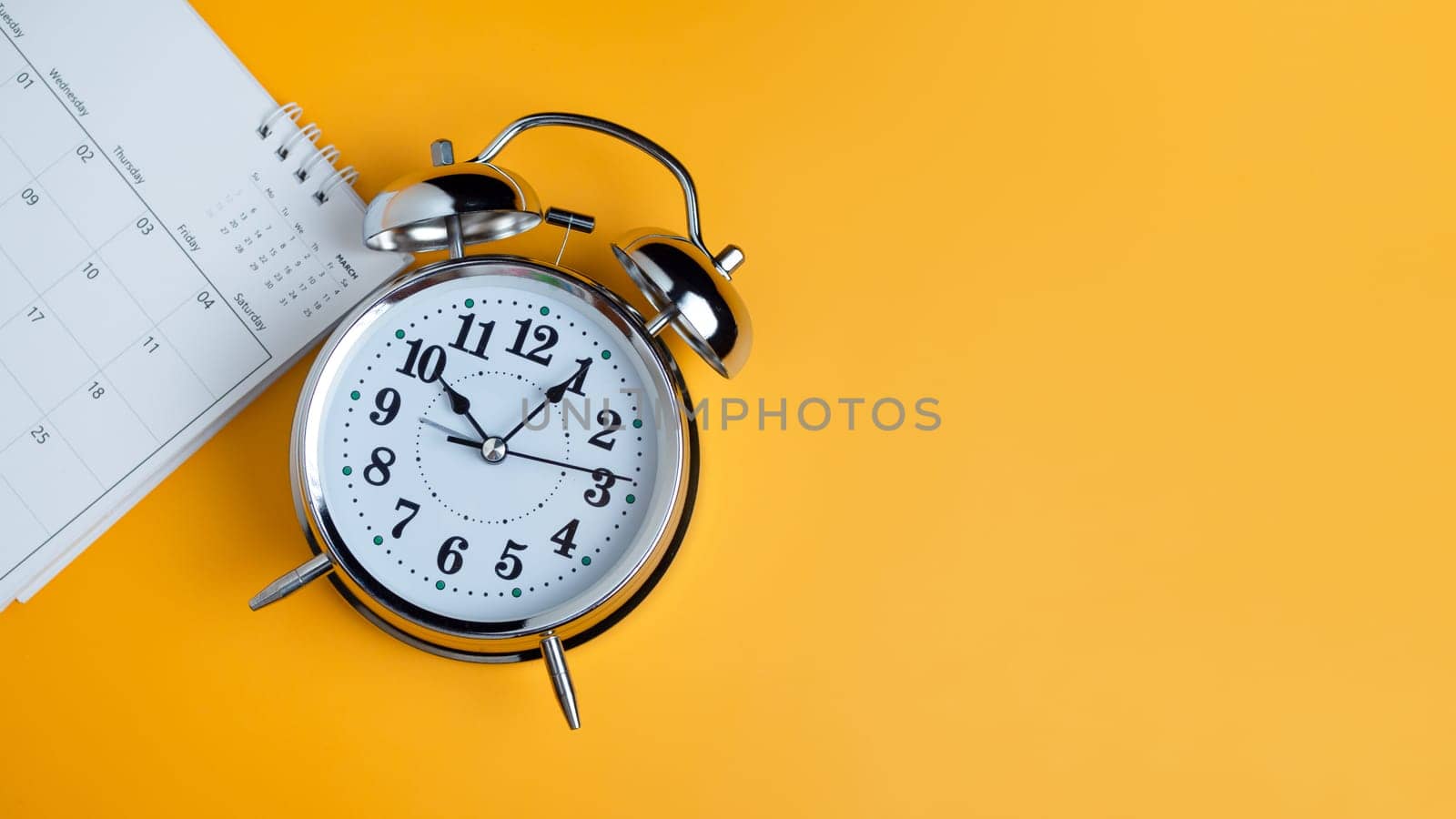 Top view of calendar and alarm clock on yellow background, planning for business meeting or travel planning concept