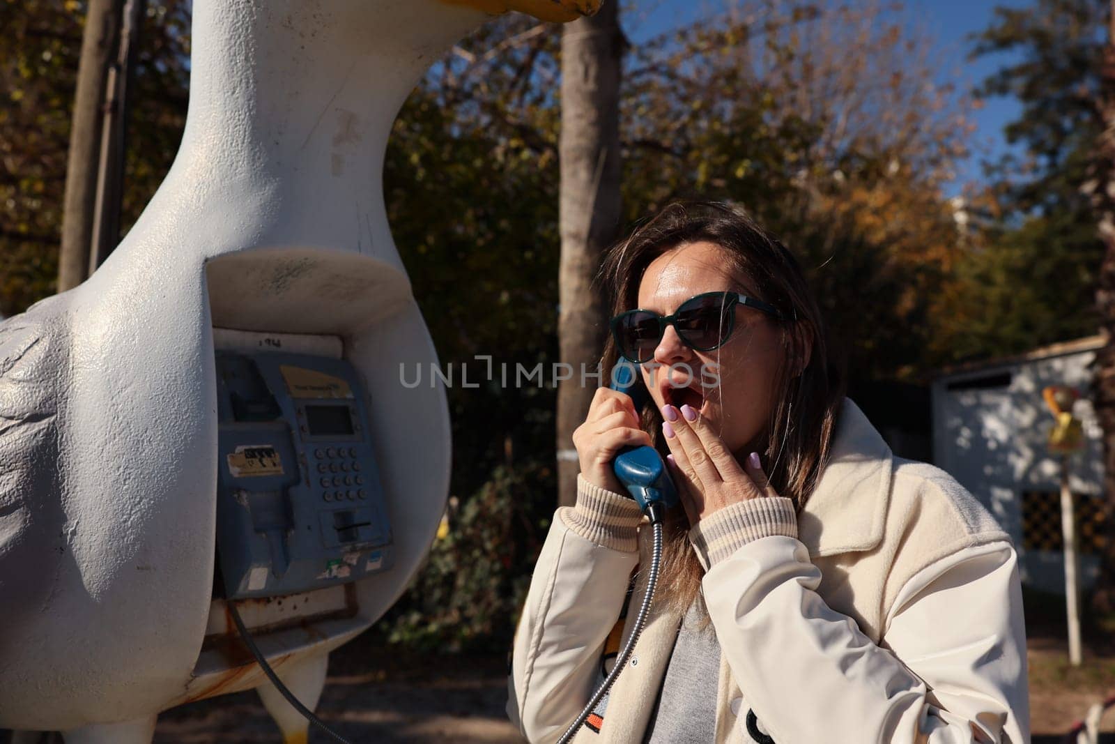 A woman has an unexpected reaction while using a unique phone booth that is shaped like a cheerful duck