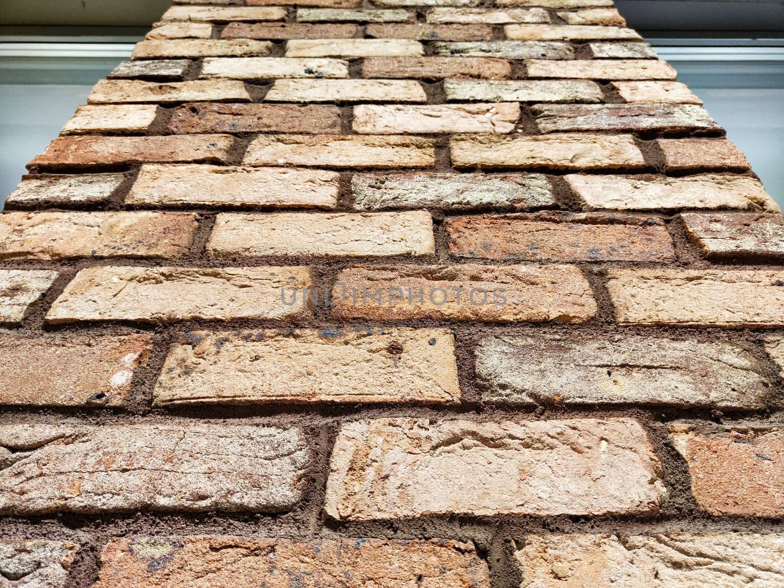Close-up view of a brick wall showcasing various textures and colors, providing an ideal background for text and design.
