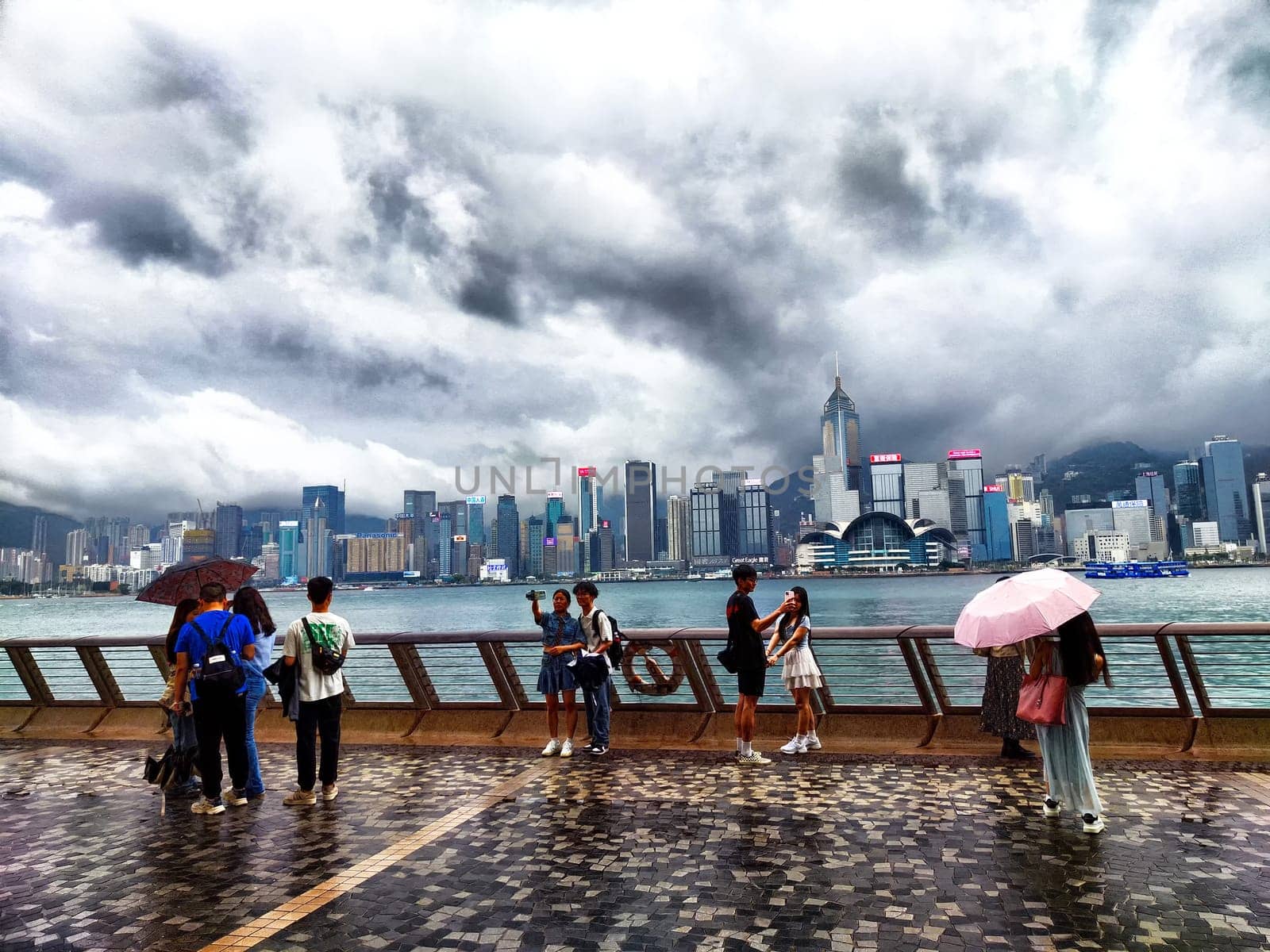 Hong Kong - April 06, 2024: Foggy skyline view of Hong Kong's Victoria Bay on a cloudy day with people enjoying the scenery