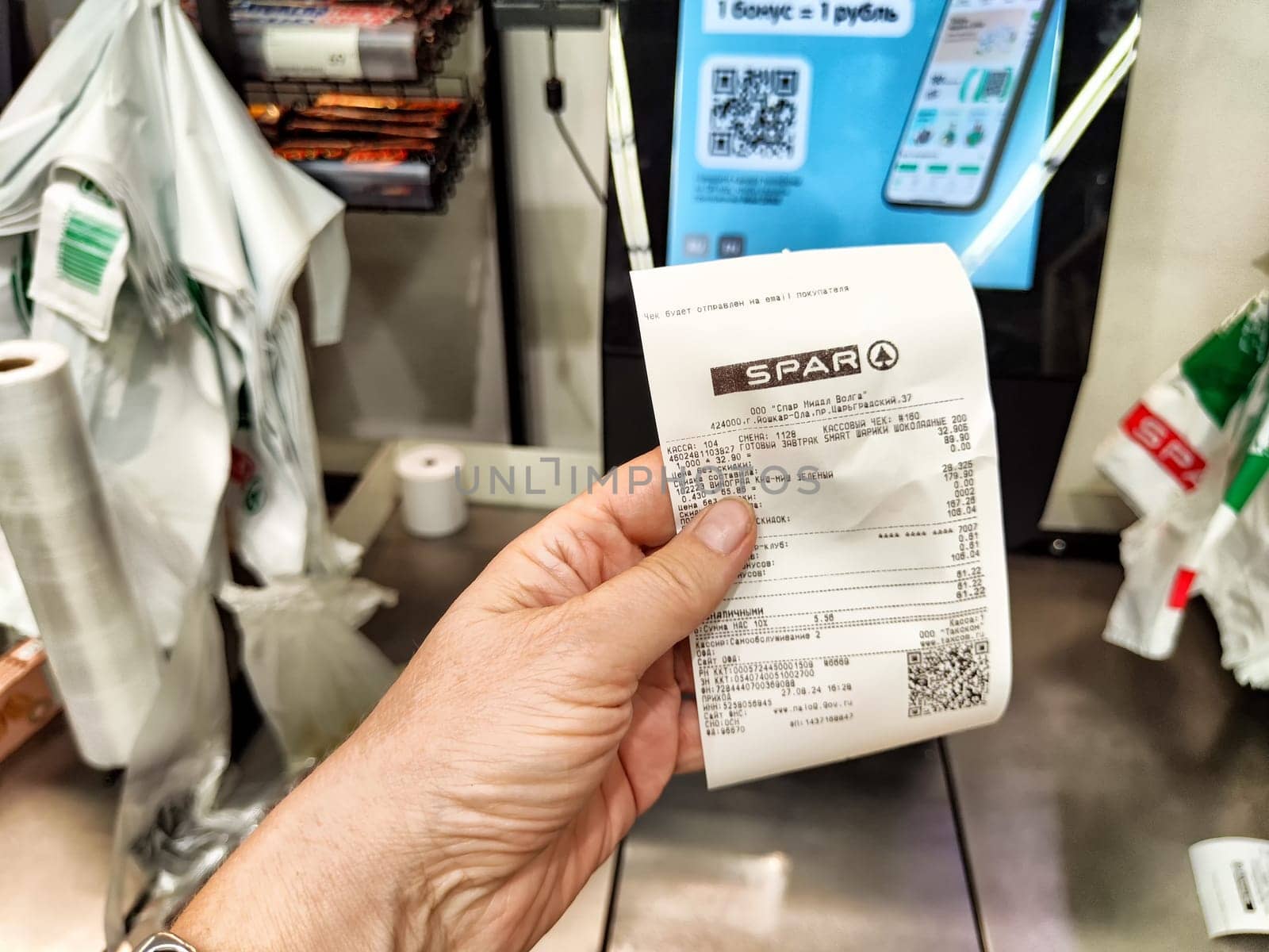 Kazan, Russia - August 27, 2024: Customer holds a receipt at a self-service checkout in a grocery store in Kazan, Russia, showcasing modern shopping technology.