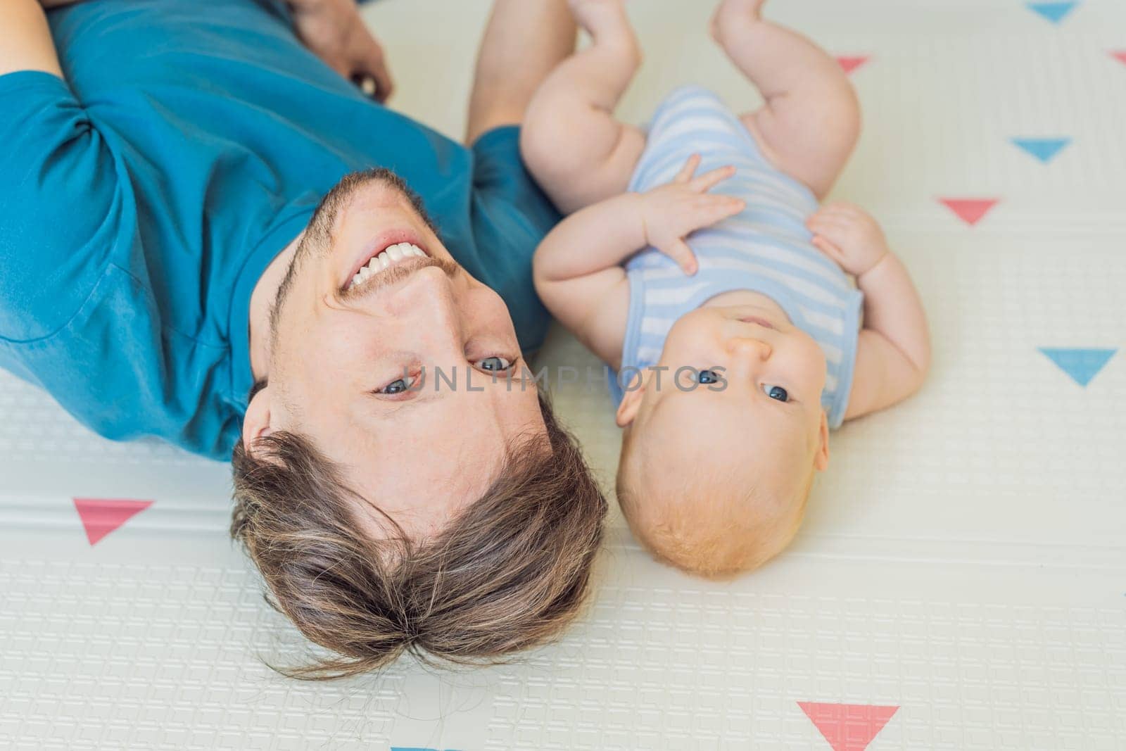 A loving father lies next to his 3-month-old baby, safely secured in a cozy infant cocoon with a special safety belt. Heartwarming family bonding moment. Parenthood, love, and baby care concept.