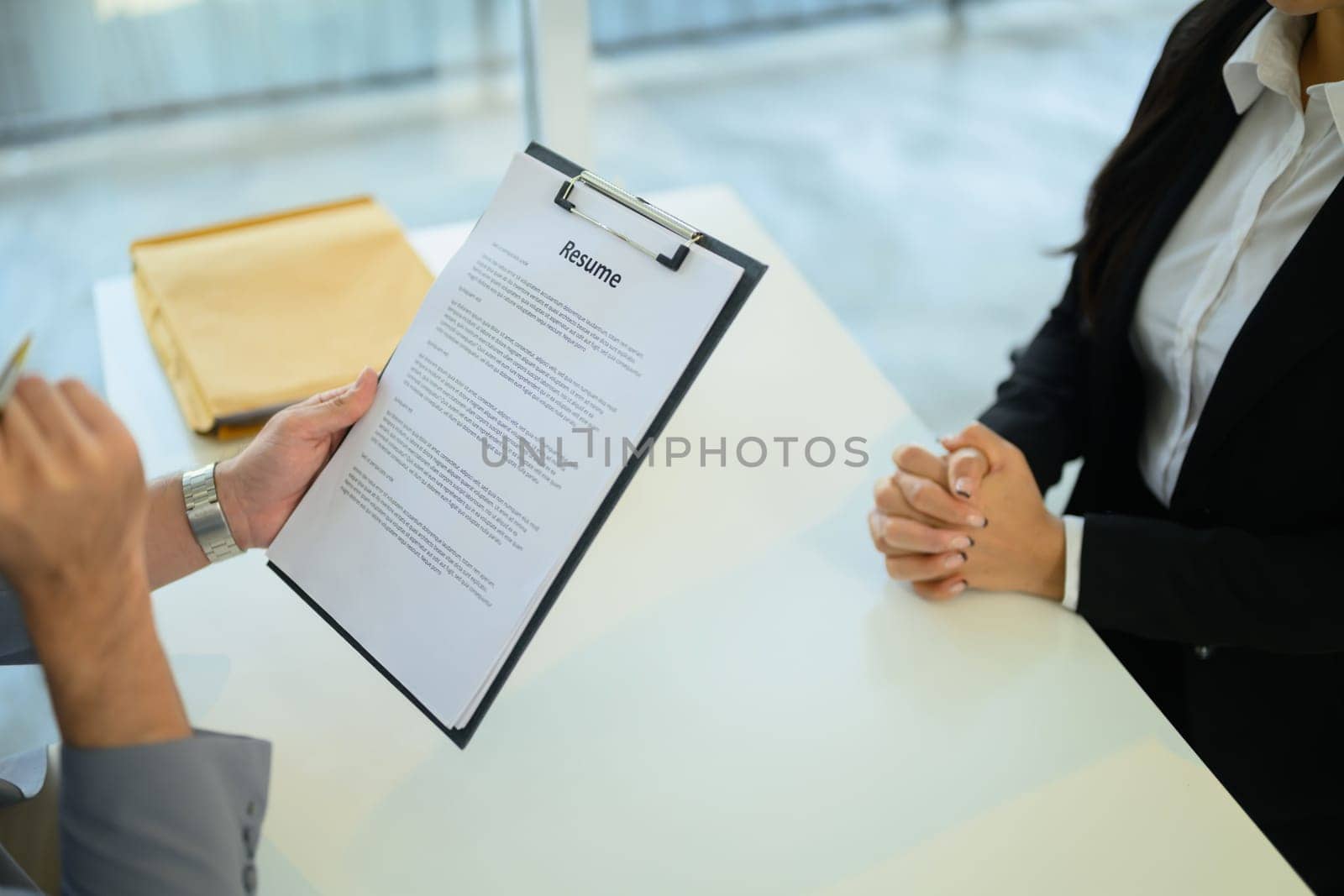 Cropped shot of employer holding a clipboard listens and evaluates candidate during an interview..