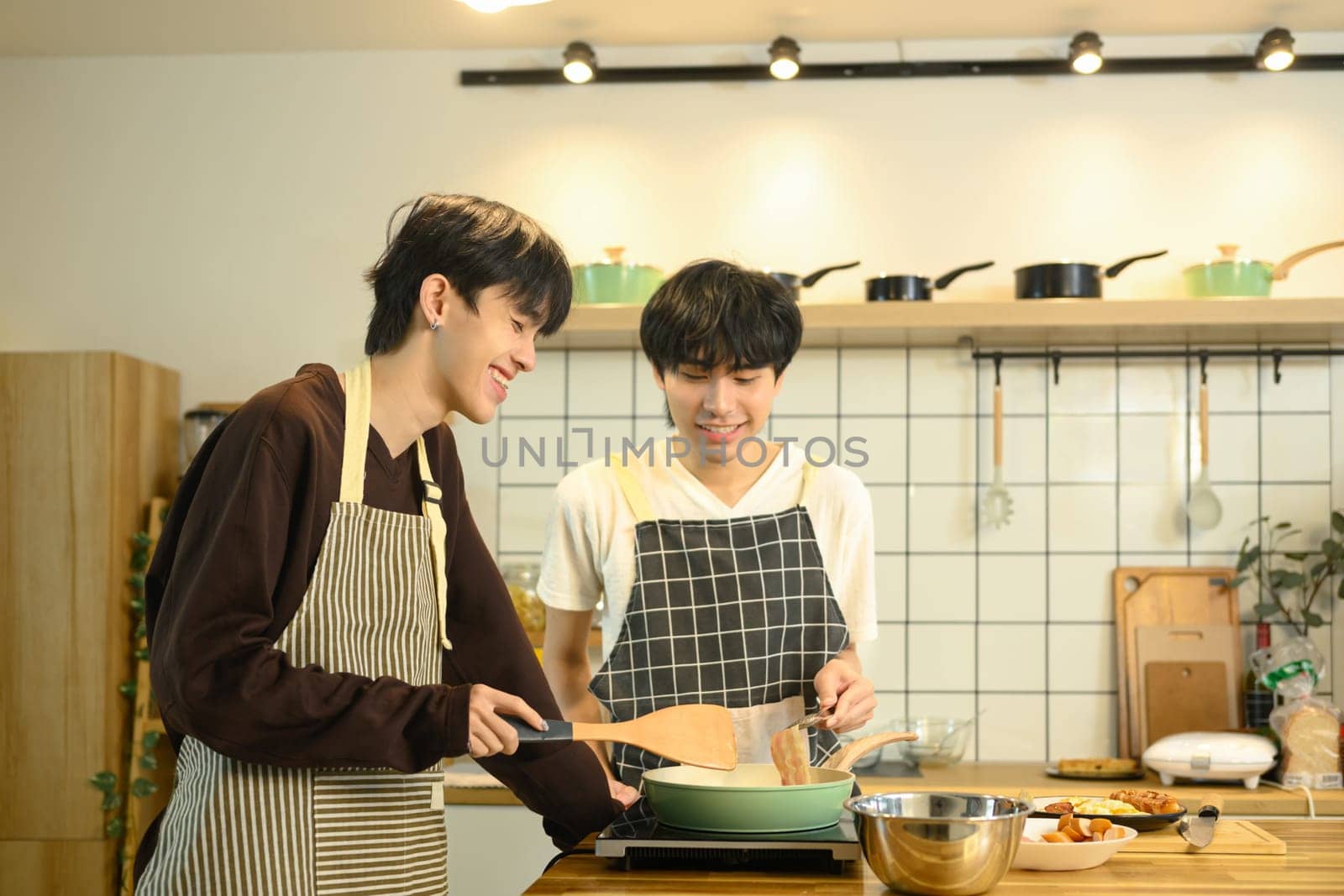 Happy gay couple enjoys cooking together in their home kitchen.