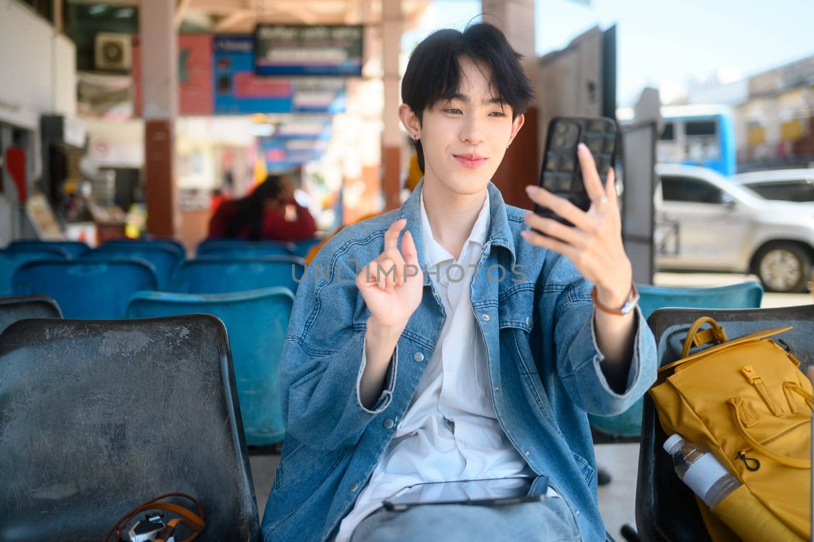 Cheerful young traveler making a video call at in a public transportation terminal.