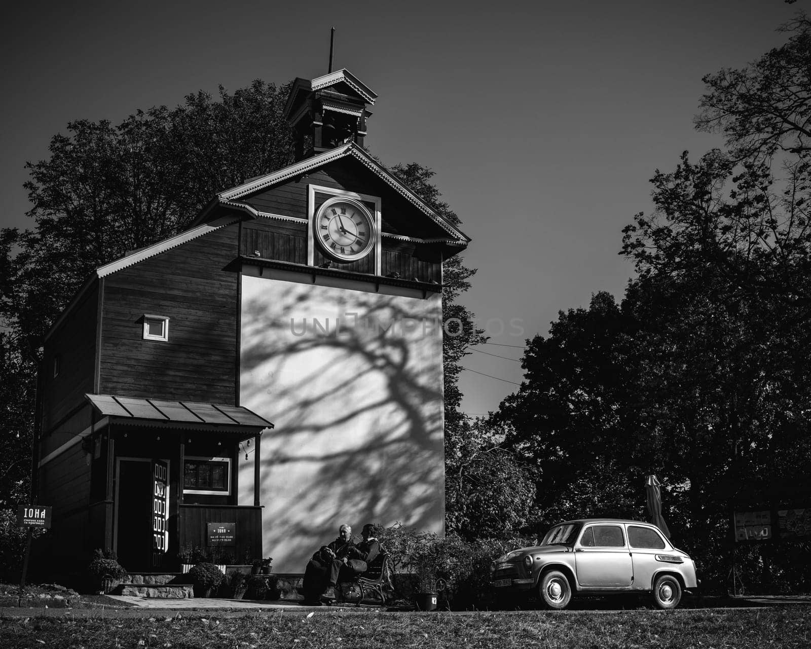 A charming historical building showcasing a beautiful clock tower alongside a vintage car in a picturesque setting