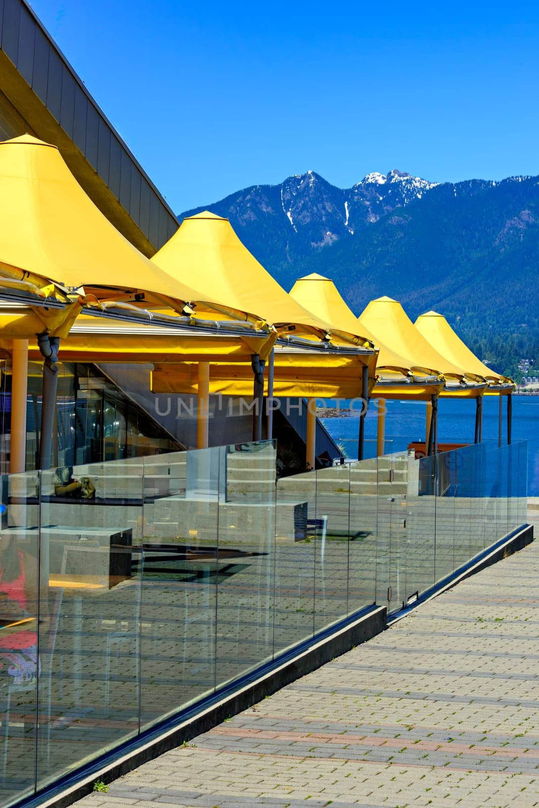 Yellow canopy of street cafe on waterfront in Vancouver with mountains background