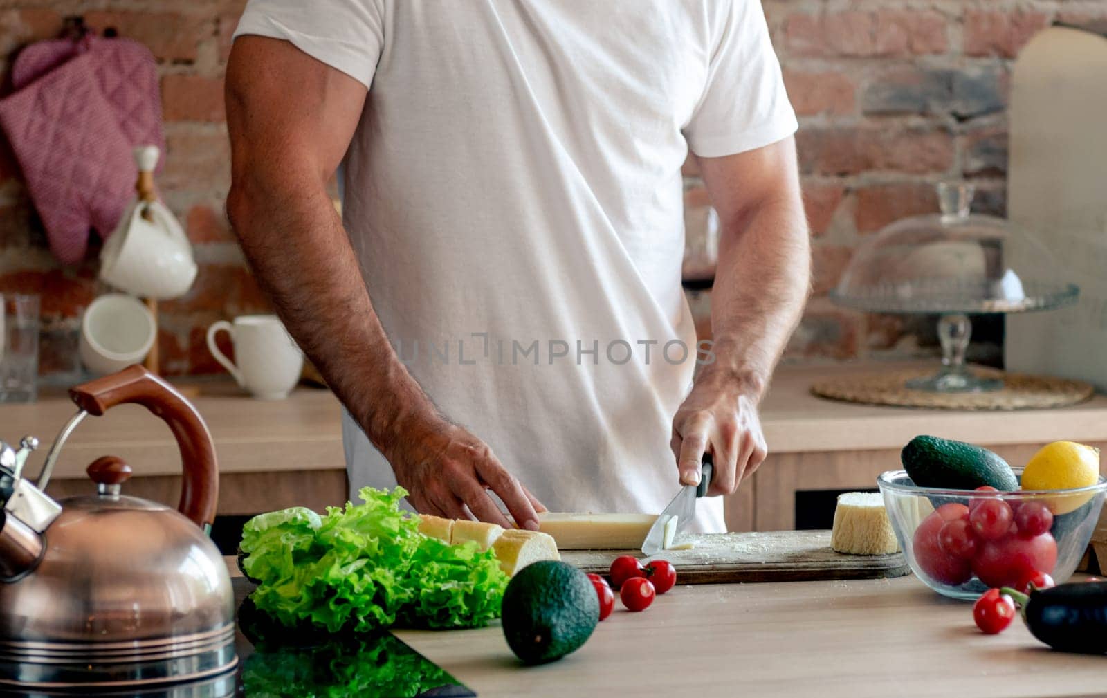Athletic Man Cutting Cheese On A Cutting Board For A Healthy Breakfast In The Kitchen