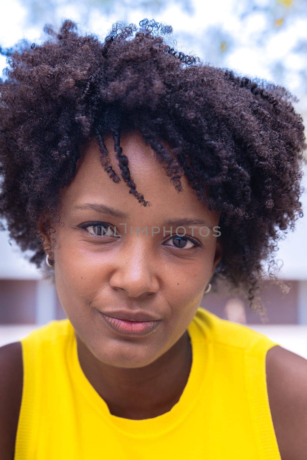 Portrait of black woman with a smiling, Focus on her facial features and natural beauty, captured outdoors with soft lighting and an urban background.