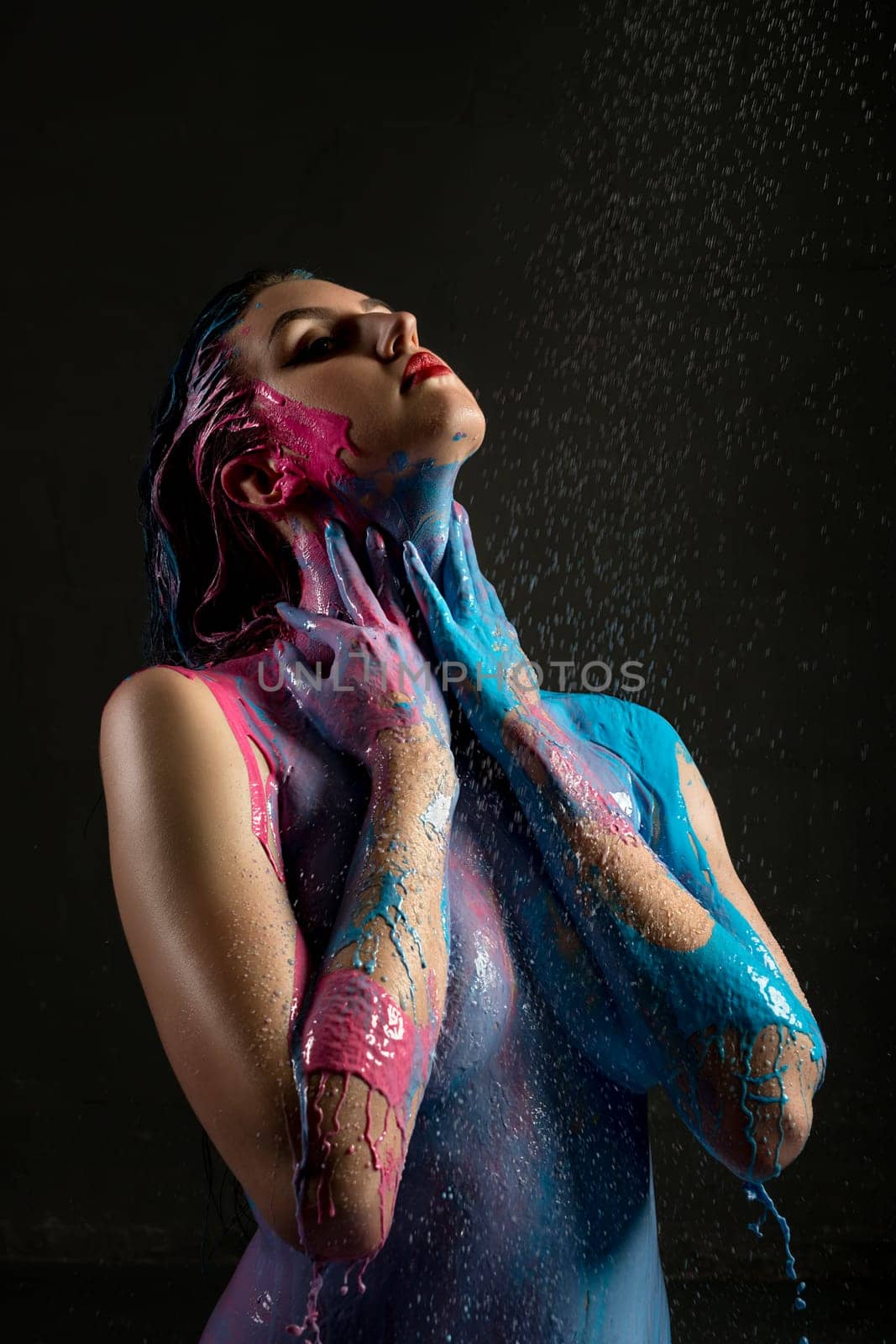 Nude woman with colour bodyart view against black background