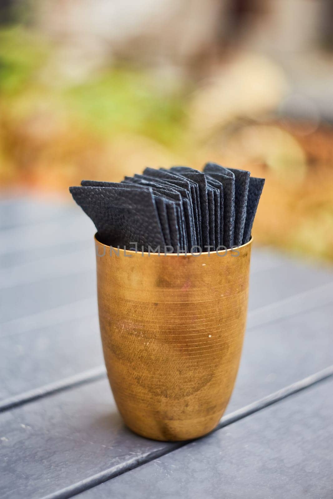 Black paper napkins in a copper cup. Serving. An outdoor cafe. Indian cuisine.