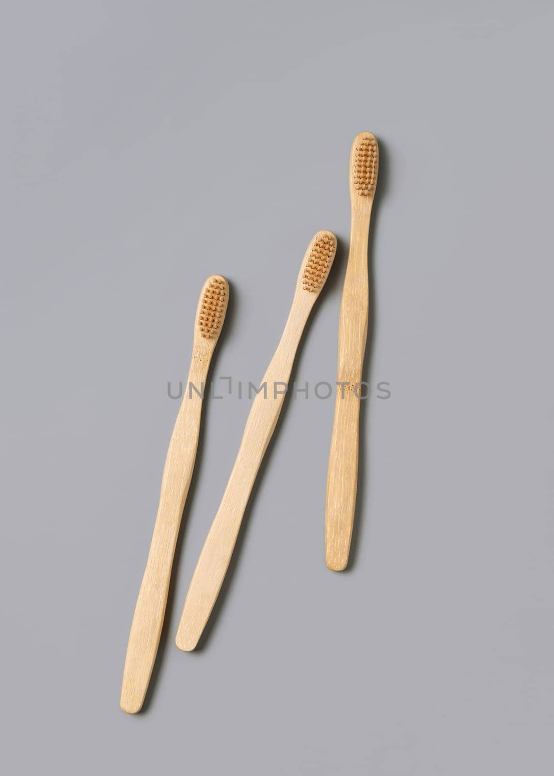 Three biodegradable bamboo toothbrushes on a light gray background top view, copy space. Zero waste and no plastic concept.
Natural personal accessories for tooth care, minimal style aesthetic flatlay