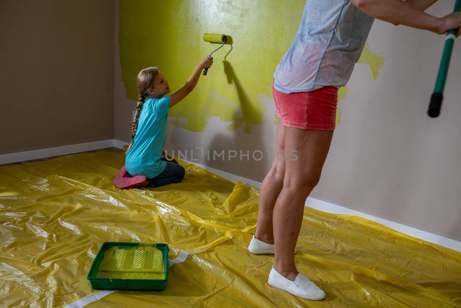 A child and parent joyfully painting a wall in vibrant colors, showcasing family bonding and creativity