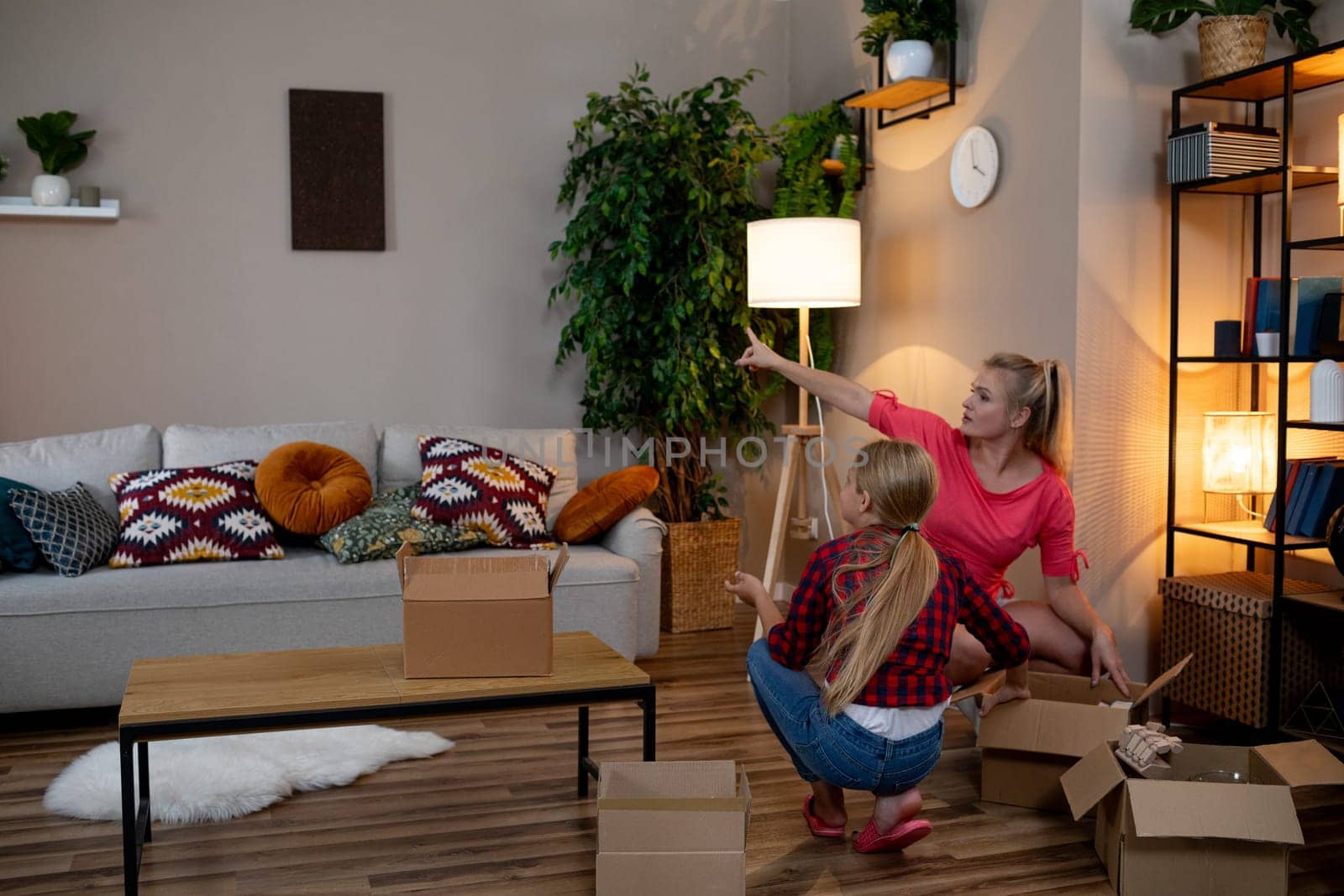 A group of women unpacking various boxes while artfully decorating their chic and stylish living room space