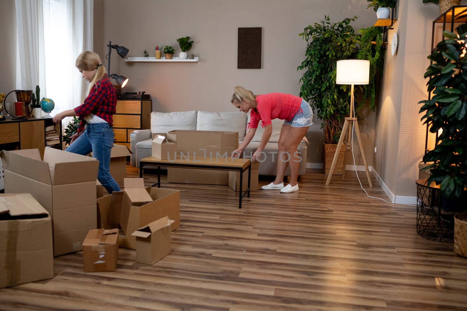 Women cheerfully unpacking in a stylish room filled with boxes and plants, creating a vibrant atmosphere