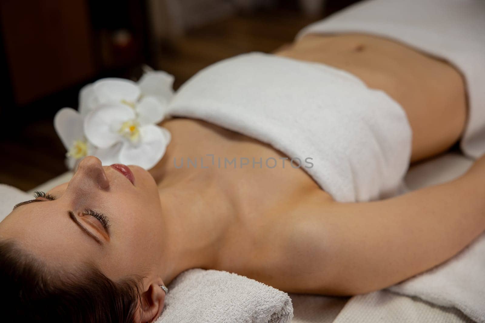 A serene and tranquil spa scene features a woman receiving soothing treatment, surrounded by calming elements