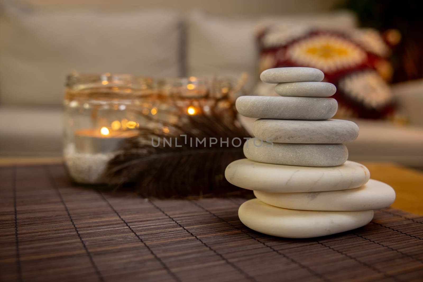A beautifully serene arrangement of carefully stacked stones placed beside glowing candles and soft textures
