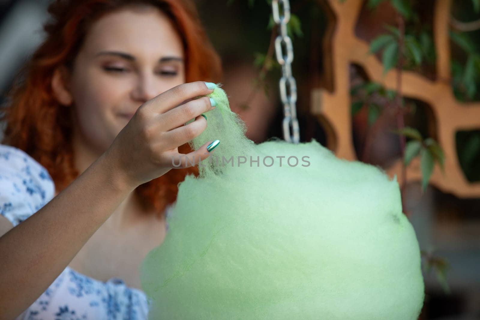 A young woman joyfully creates cotton candy, capturing a delightful moment at a vibrant festive gathering