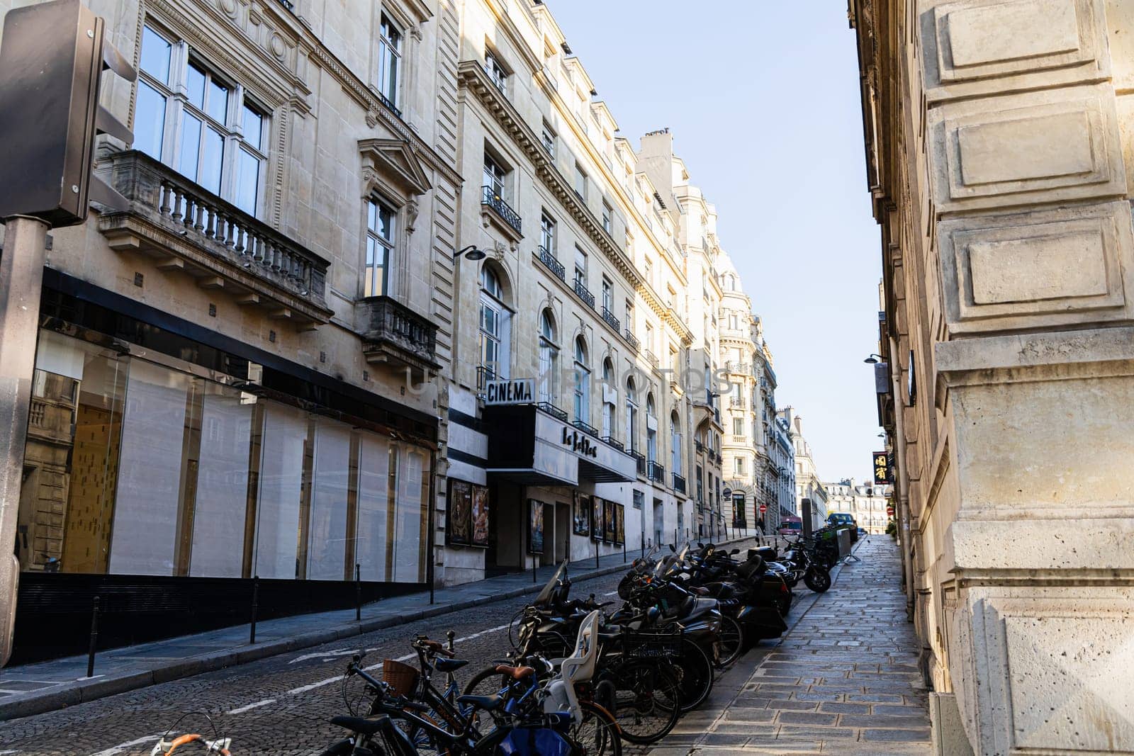 A narrow street in Paris with beautiful buildings and parked cars. Paris, France - November 24, 2024