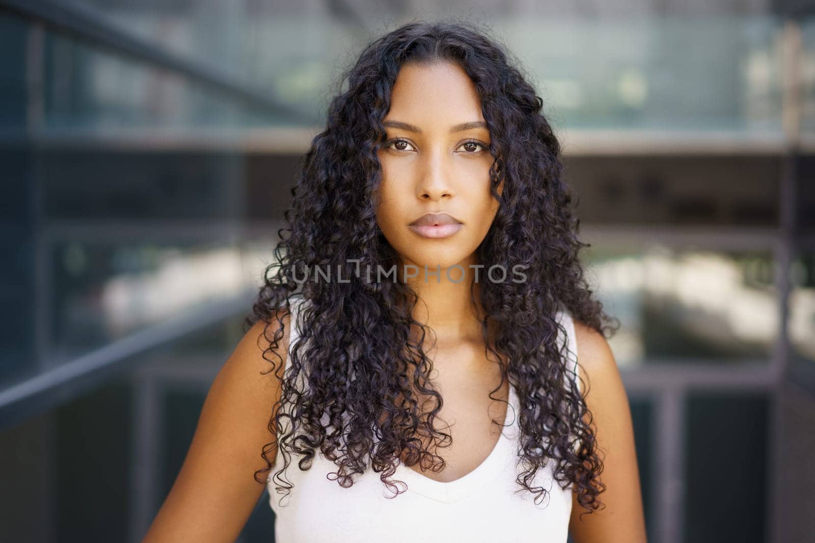 In an energetic urban setting, a confident young woman with beautiful curly hair stands out, exuding strength and grace, captivating viewers with her charming personality and magnetic presence