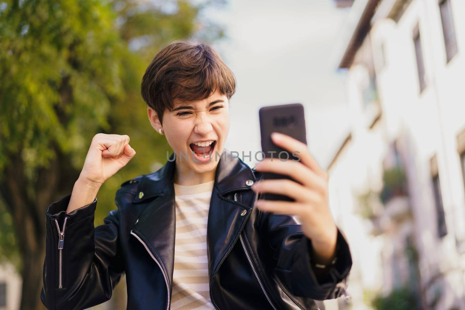 A young person joyfully takes a selfie outdoors, radiating excitement and embodying a vibrant modern lifestyle filled with moments of happiness and playful expression in the natural surroundings