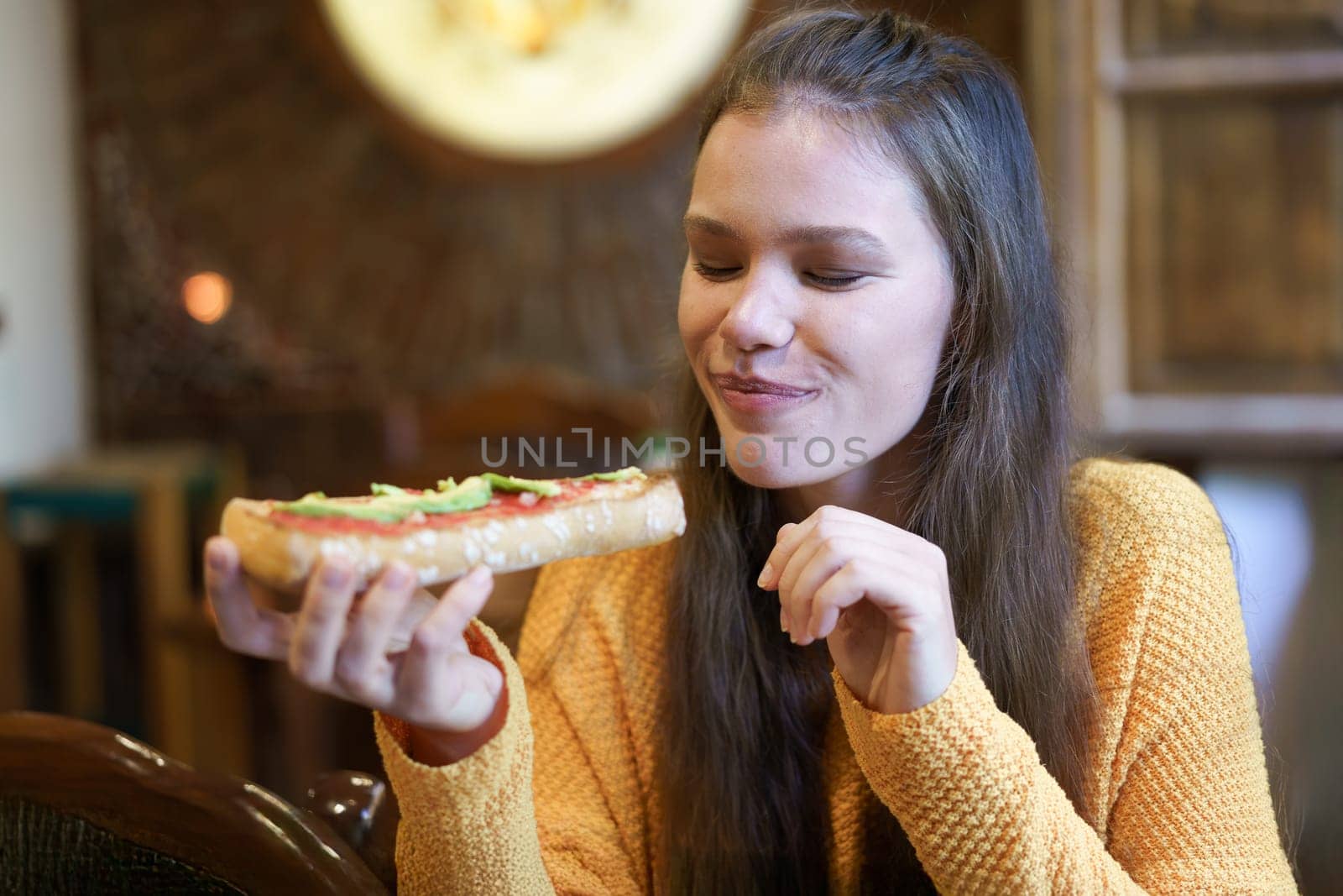 A woman delights in savoring a freshly made sandwich, truly embodying the joy that comes from good food served in a warm, inviting atmosphere that significantly enhances her overall experience