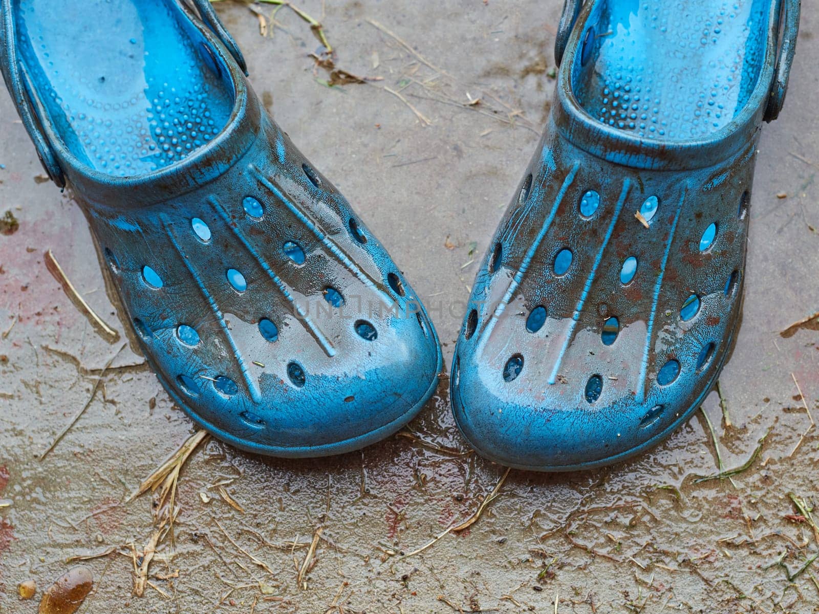 blue flip-flops for cottages dirty from the weather on the background of a concrete path